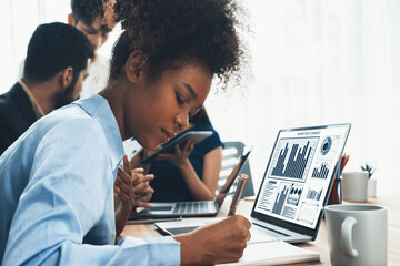 Young african businesswoman working together and discussing in corporate office with multicultural coworkers. Professional and diversity teamwork discuss business plan on desk. Concord