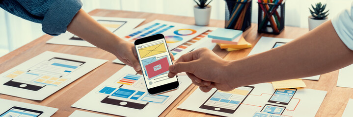 Wall Mural - panorama shot of front-end developer team brainstorming ui and ux designs for mobile app on paper wi