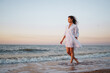 © maxbelchenko - Slender young woman in airy white is enjoying the sunset light on the seashore. Summer time. Travel, weekend, sunny, fun, positive mood. Active lifestyle.