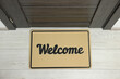 © New Africa - Beige doormat with word Welcome on white floor near entrance, top view