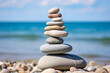 Pile of smooth stones stacked on a pebbly beach, symbolizing balance and stability, with the ocean backdrop