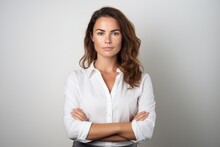 A Portrait Photo Of A Beautiful Businesswoman Lady In A White Suit Shirt Having Her Arms Folded And Watching Forward In The Camera. White Background. Studio Photography For Ads. Generative AI