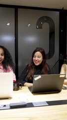 multiracial mixed group of four people students employees sitting at table using notebooks in meeting room