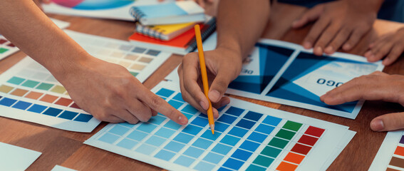Leinwandbilder - Graphic designer brainstorm logo and graphic art at busy creative studio workshop. Experiment and brainstorm color palette and pattern at workspace table for creative design. Panorama shot. Scrutinize