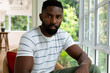 © wavebreak3 - Portrait of african american man sitting in woven armchair at sunny home