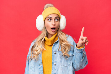 Wall Mural - Young pretty Uruguayan woman wearing winter muffs isolated on red background background thinking an idea pointing the finger up