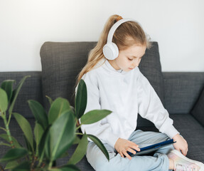 Wall Mural - Little girl with headphones and tablet  at home