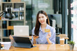 © Nuttapong punna - Asian Woman using smart phone for mobile payments online shopping,omni channel,sitting on table,virtual icons graphics interface screen in morning light.
