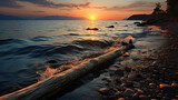 Fototapeta Łazienka - A tranquil coastal scene featuring a beached driftwood log, silhouetted against the setting sun.