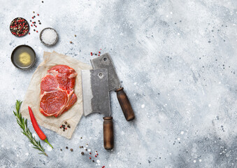 Wall Mural - Fillet of raw beef rib eye steak on with meat cleaver,salt and pepper on light kitchen table background