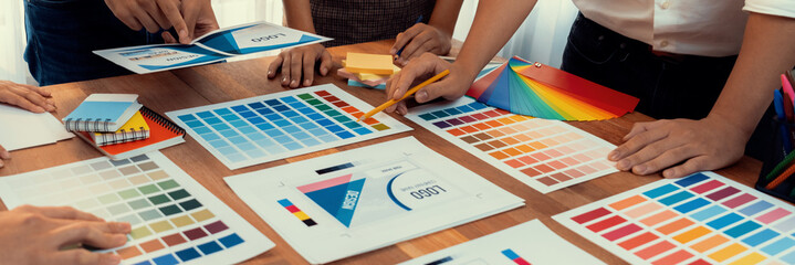 Leinwandbilder - Graphic designer brainstorm logo and graphic art at busy creative studio workshop. Experiment and brainstorm color palette and pattern at workspace table for creative design. Panorama shot. Scrutinize