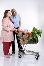 Senior Couple Posing With A Shopping Cart Isolated On White Background.