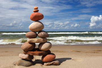 Wall Mural - Stone zen pyramid made of colorful pebbles on the beach against a stormy sea.