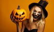 Woman with halloween makeup holding carved pumpkin on a orange background