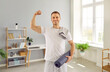 © Studio Romantic - Portrait of happy fit male athlete after active fitness workout at home. Smiling handsome sporty man in white T shirt standing in living room, holding sports mat and showing strong biceps arm muscles