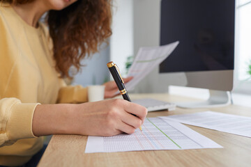 Lady accountant working with balance sheets in office. Female worker checking columns on paper business spreadsheet, reviewing enterprise loss and profit figures. Close up. Budget concept background