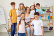 © Studio Romantic - Portrait of group of cheerful little students making horns with their fingers and their friendly young teacher. Joyful elementary school students laughing at camera with creative teacher in classroom.