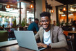 © MVProductions - African American man working on a laptop computer in a busy cafe, a portrait of a successful person