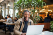 © MVProductions - African American man working on a laptop computer in a busy cafe, a portrait of a successful person