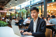 © MVProductions - Asian man working on a laptop computer in a busy cafe in the city, a portrait of a successful man