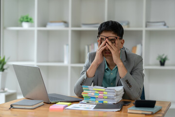 tired business man sleepy and bored from sitting at a desk for a long time and has office syndrome