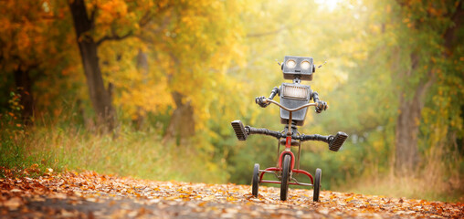 happy humanoid robot rides a bicycle along the autumn alley. robotic object experiences feelings and