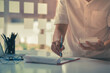 © PixelPlex - Close up of a man hands checking smart phone calendar and writing on agenda in the night at home