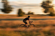 Cyclist on a gravel bike in a field at sunset. Motion blur effect. Travel and active lifestyle concept.