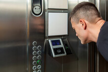 A Man Shows His Face To A Fingerprint Access Control Terminal With A Facial Recognition Function Installed In The Elevator