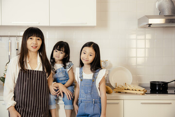 portrait group of asian mother and daughter taking at home kitchen happy together