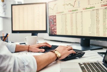 Businessman at work. Cropped photo of male trader's hands with watch on his wrist working on computer and analyzing financial data while sitting in his office.