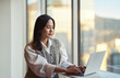 © insta_photos - Young pretty Asian business woman employee or student working on laptop in corporate office. Professional businesswoman company worker using computer, typing, elearning sitting at desk.
