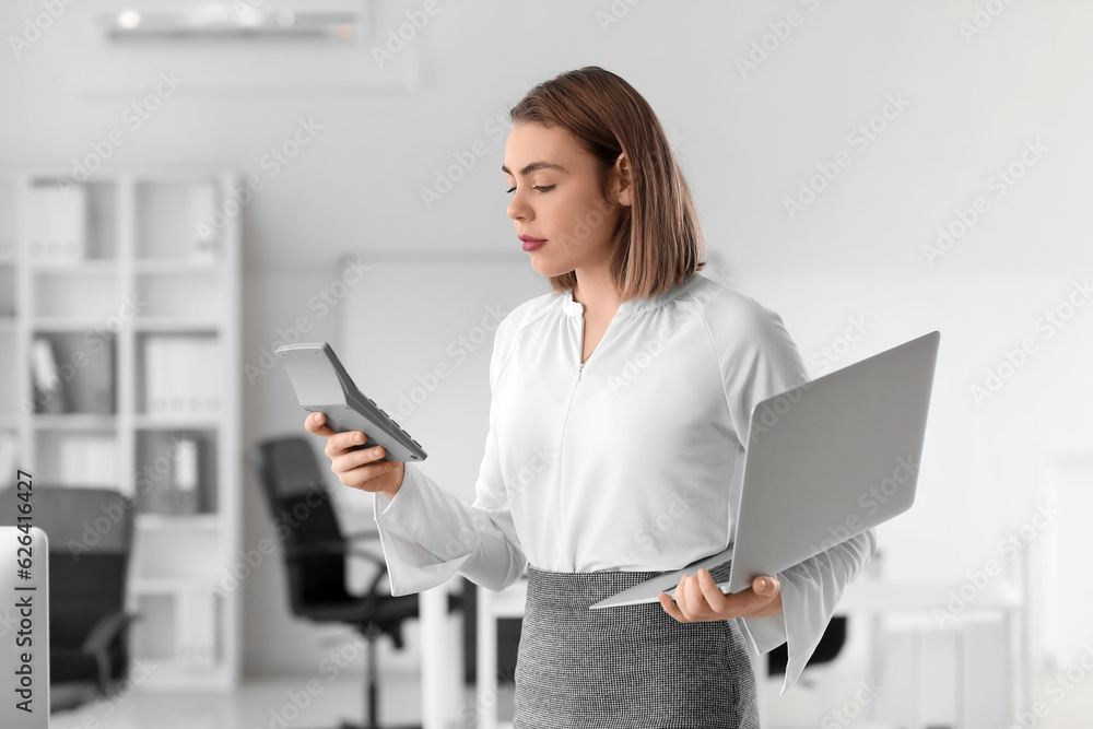 Female accountant with calculator and laptop in office
