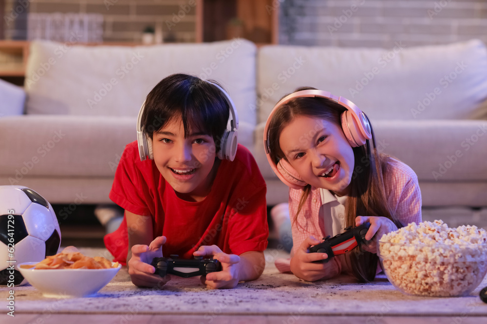 Little children playing video game at home in evening