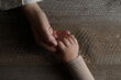 © New Africa - Woman holding hands with her granddaughter at wooden table, top view. Space for text