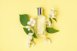 Composition with bottle of perfume and beautiful jasmine flowers on yellow background