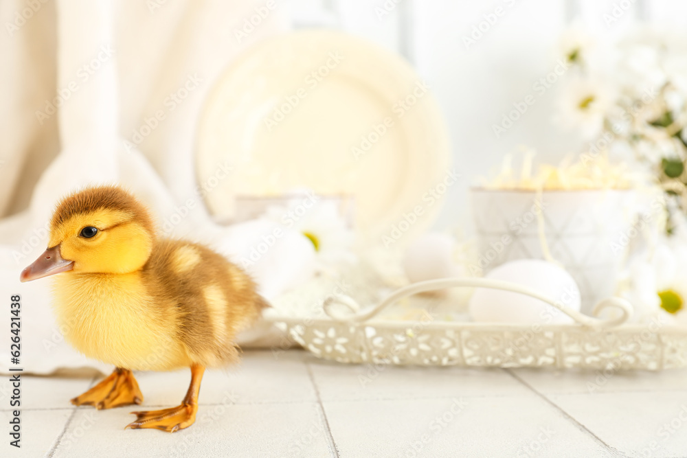 Cute duckling, tray with cup and chamomile flowers on white tile table