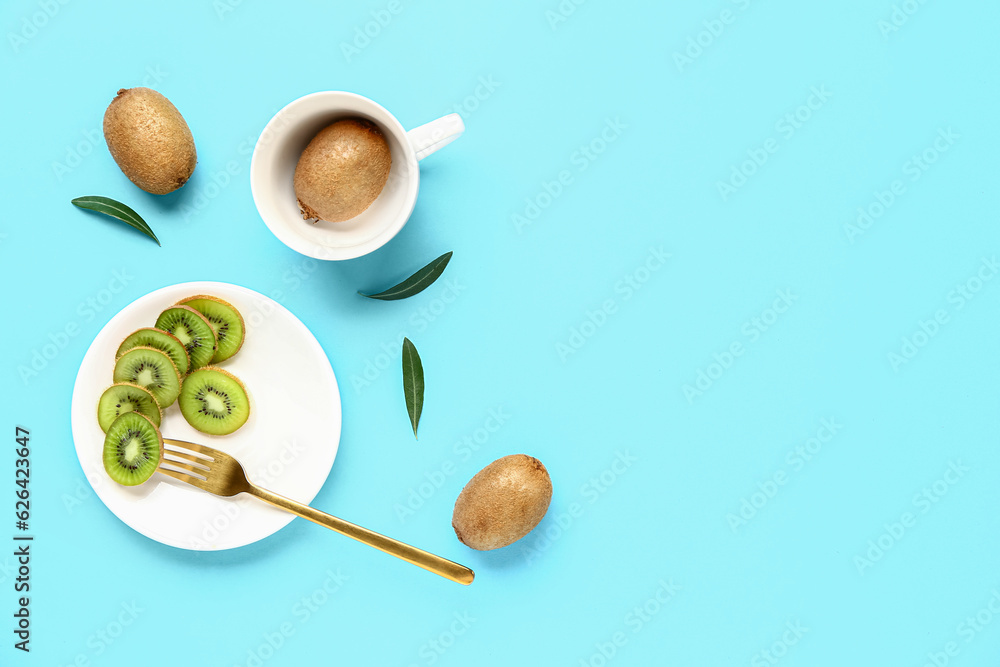 Plate and cup with fresh kiwi on turquoise background