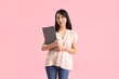© Pixel-Shot - Female Asian teacher with clipboard on pink background