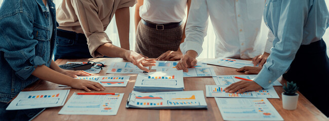 Leinwandbilder - Analyst team utilizing BI Fintech to analyze and pointing at financial dashboard paper office. Businesspeople examining report paper on table for business insight. Panorama shot. Scrutinize