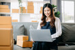 © Nuttapong punna - Young asian business owner woman prepare parcel box and standing check online orders for deliver to customer on tablet, laptop Shopping Online concept..
