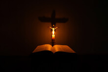 Light Candle With Holy Bible And Cross Or Crucifix On Old Wooden Background In Church.Candlelight And Open Book On Vintage Wood Table Christianity Study And Reading In Home.Concept Of Christ Religion