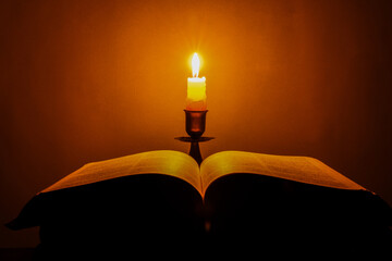 Sticker - Candle with bible on a old oak wooden table. Beautiful gold background. Religion concept.