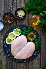 Wall Mural - Fresh raw chicken breasts on cutting board with spices on wooden background
