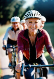 Fototapeta  - A smiling middle-aged woman wearing a helmet is enjoying a leisurely, sporty bike ride with friends. She smiles at the camera as they ride along a country road. 