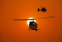 Silhouette Helicopter Military Army Practice Training Flying Survey  Area With Orange Sun Sky Background.