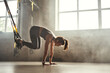 © Friends Stock - Doing TRX exercises. Young athletic woman in sports clothing training legs with trx fitness straps in the gym.