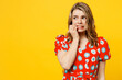 Young minded confused mistaken upset sad caucasian woman she wearing red dress casual clothes looking aside biting nails fingers isolated on plain yellow background studio portrait. Lifestyle concept.
