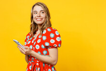Side View Young Smiling Cheerful Satisfied Woman She Wear Red Dress Casual Clothes Hold In Hand Use Mobile Cell Phone Look Camera Isolated On Plain Yellow Background Studio Portrait Lifestyle Concept