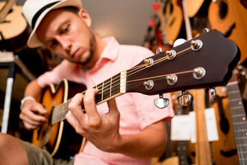 Wall Mural - Young musician tuning a classical guitar in a guitar shop